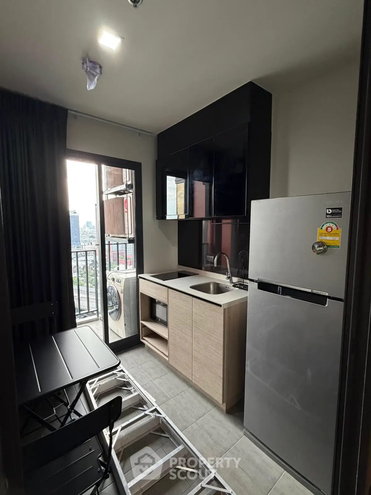 Modern compact kitchen with balcony view, featuring sleek cabinetry and appliances.