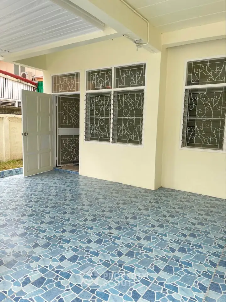 Spacious tiled patio with open door and decorative window grills, perfect for outdoor relaxation.