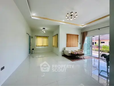 Spacious living room with modern lighting and large windows opening to a balcony.