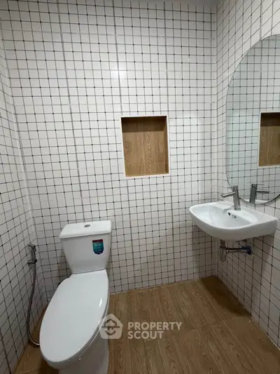 Modern bathroom with white tiled walls, wooden floor, and sleek fixtures.