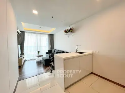 Modern open-layout living room with sleek kitchen and large windows.