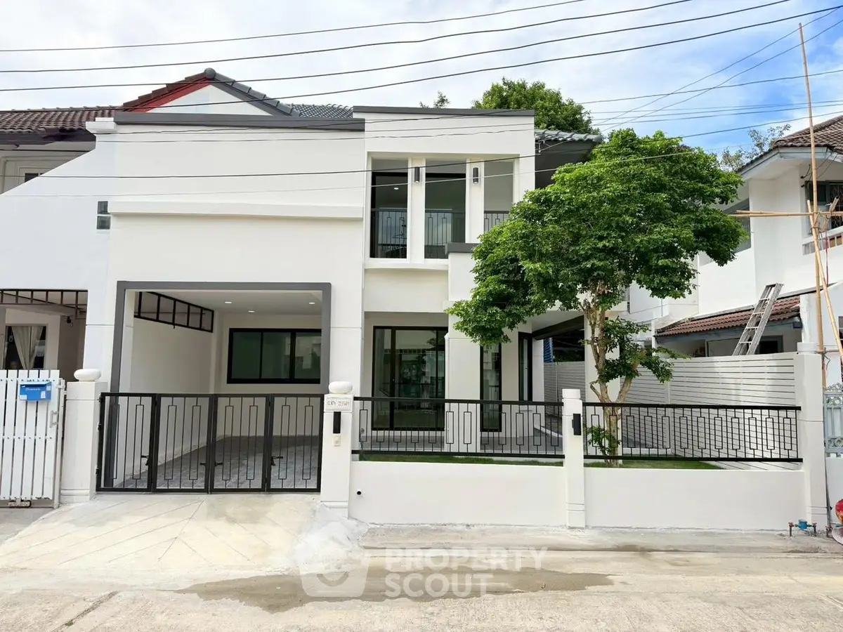 Modern two-story house with sleek design and spacious driveway in a suburban neighborhood.
