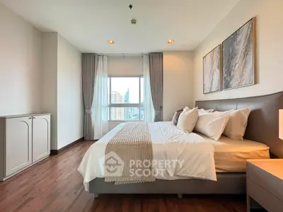 Spacious modern bedroom with city view, elegant decor, and natural light.