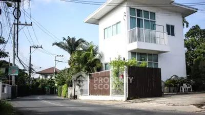Modern two-story corner house with a spacious balcony, surrounded by lush greenery in a serene neighborhood, perfect for families seeking comfort and privacy.