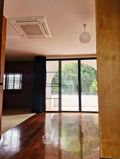 Spacious living room with wooden floors and large sliding glass doors to balcony.
