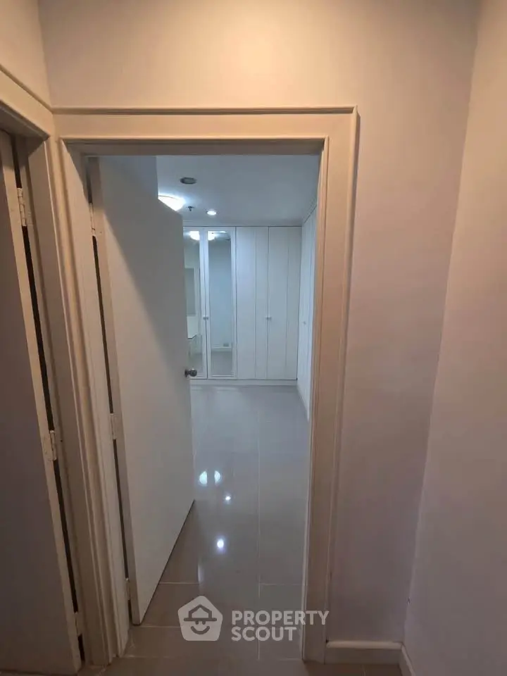 Spacious hallway leading to a modern bathroom with sleek fixtures and ample storage.