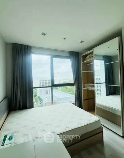 Bright bedroom with large window and modern wardrobe in a high-rise apartment.