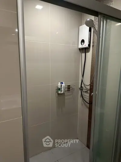 Modern bathroom shower area with sleek glass doors and wall-mounted shower unit.