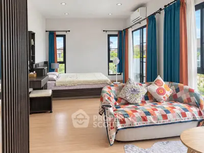 Spacious bedroom with vibrant decor and large windows offering natural light