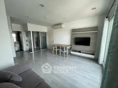 Modern living room with sleek flooring and wall-mounted TV in a bright apartment