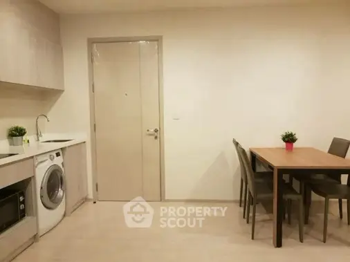Modern kitchen with washing machine and dining area in compact apartment.