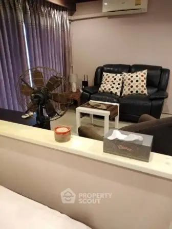 Cozy living room with leather sofa, vintage fan, and modern decor accents.