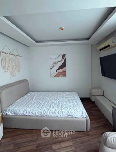 Modern bedroom with stylish decor and wall-mounted TV in a cozy apartment.