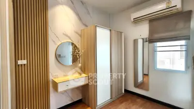 Modern bedroom with stylish wardrobe, wall mirror, and air conditioning unit.