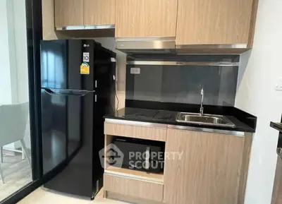 Modern kitchen with sleek black appliances and wooden cabinetry in a stylish apartment.