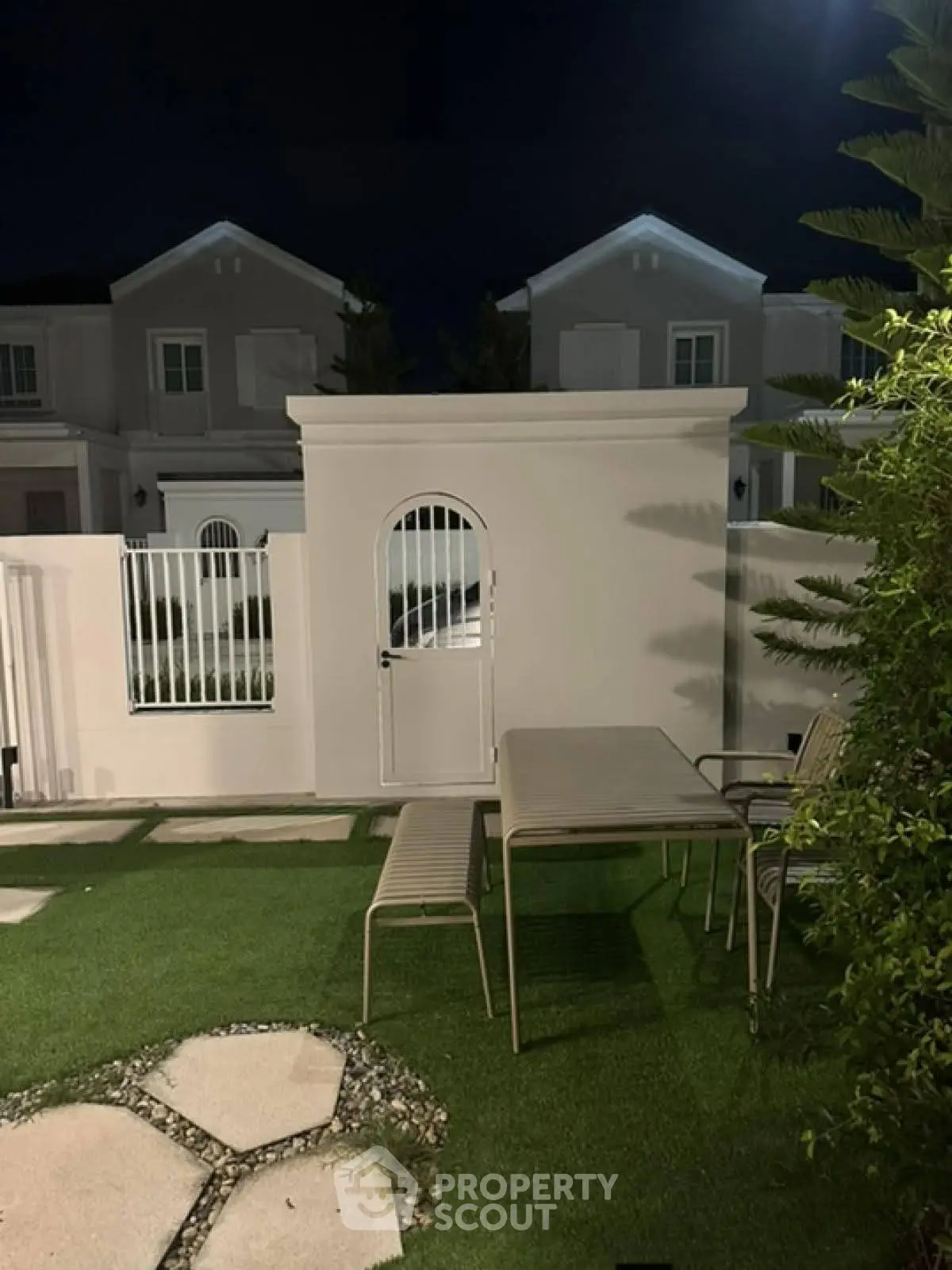 Charming night view of a garden with outdoor seating in a modern residential area.