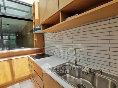 Modern kitchen with sleek cabinetry and stainless steel sink, featuring a large window for natural light.