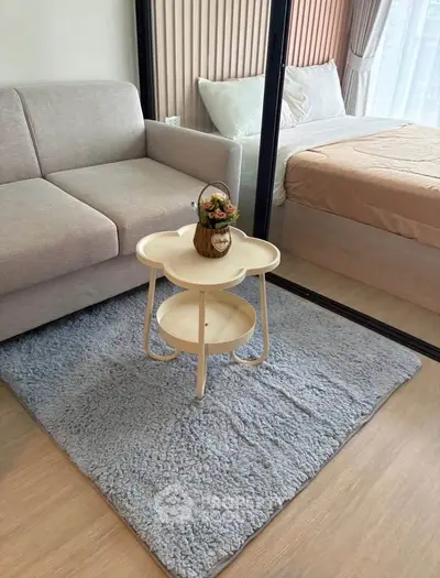 Cozy living room with modern decor and plush rug adjacent to a stylish bedroom.