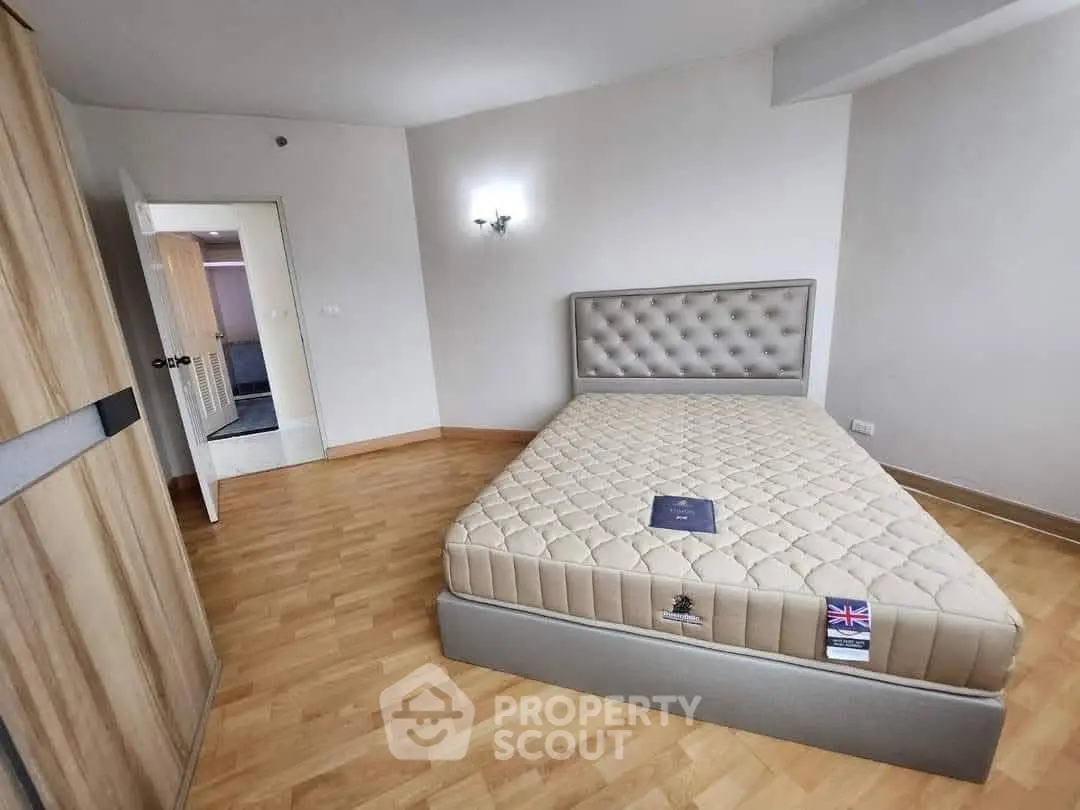 Spacious bedroom with elegant bed and wooden flooring in modern apartment.