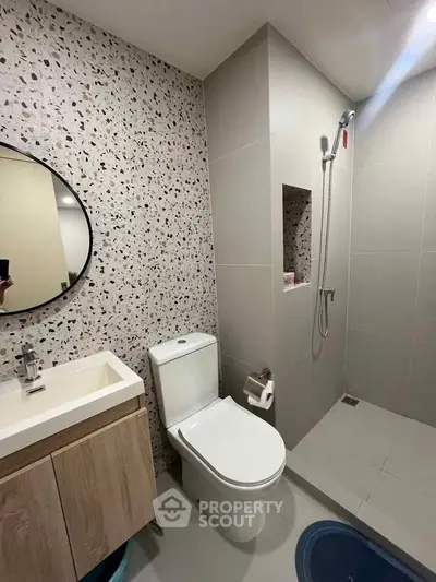 Modern bathroom with terrazzo wall, sleek fixtures, and walk-in shower in contemporary apartment.