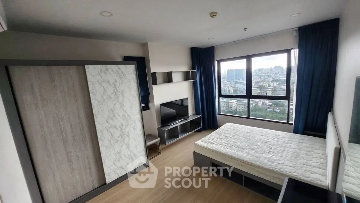 Modern bedroom with large window offering stunning city view, stylish wardrobe, and sleek TV setup.