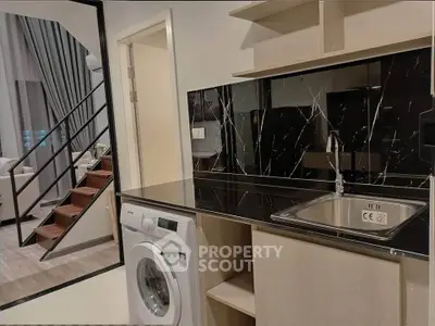 Modern duplex apartment with sleek kitchen and washing machine, featuring elegant black marble backsplash.