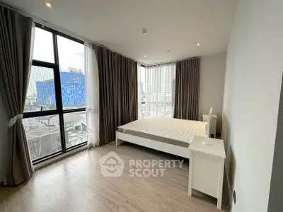 Spacious bedroom with large windows and modern decor in urban apartment