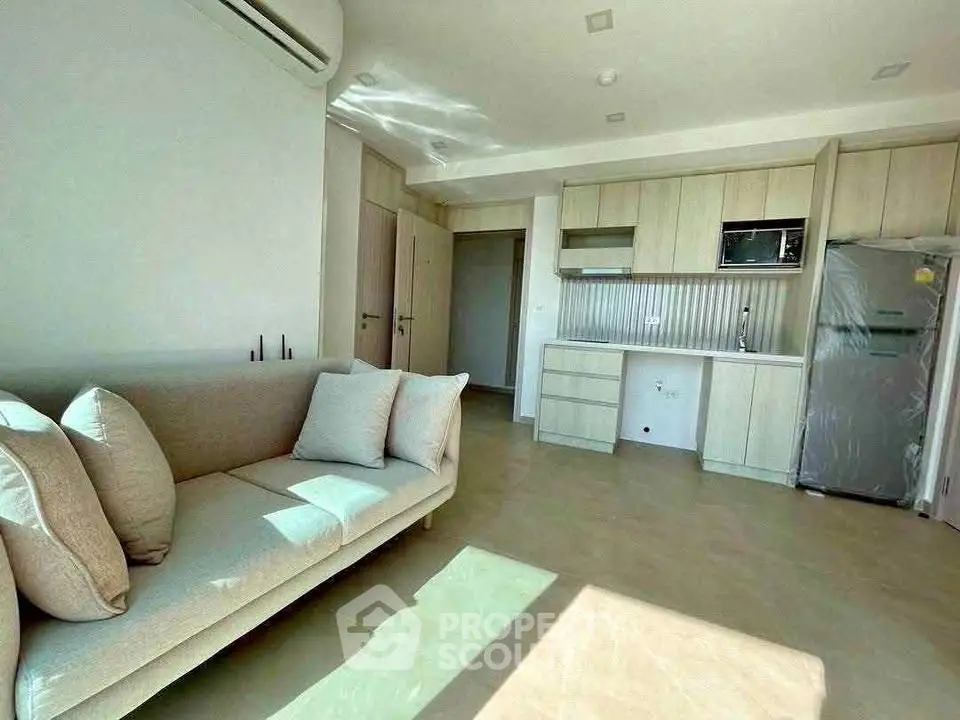 Modern living room with open kitchen, featuring sleek cabinetry and abundant natural light.