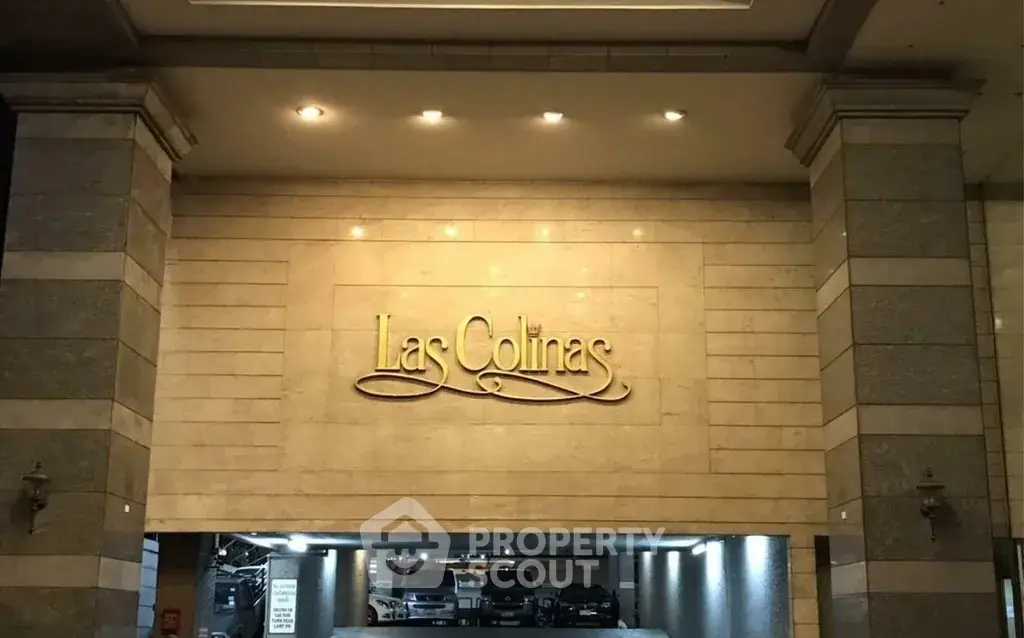 Elegant entrance of Las Colinas building with well-lit parking area.