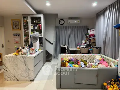 Spacious family room with playpen and modern kitchen island, ideal for family living.