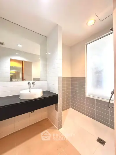 Modern bathroom with sleek design, featuring a spacious shower and elegant sink area.