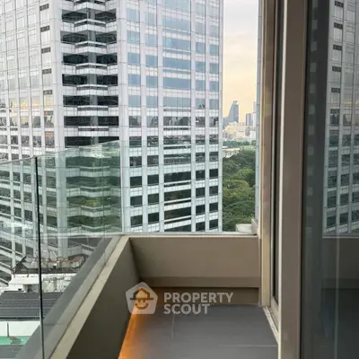 Modern balcony with glass railing offering stunning cityscape views in a high-rise building.