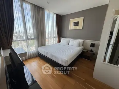 Spacious bedroom with large windows and modern decor in high-rise apartment.