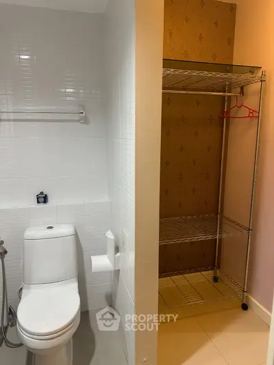 Compact bathroom with toilet and metal shelving unit, ideal for efficient space utilization.