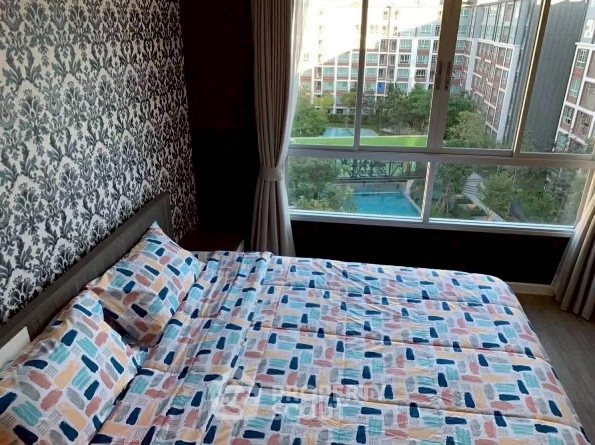 Stylish bedroom with patterned bedding and large window overlooking pool and garden view.