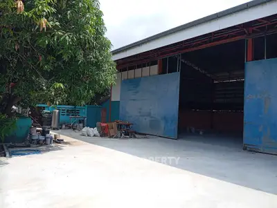 Spacious industrial warehouse with open entrance and outdoor area, ideal for storage or manufacturing.