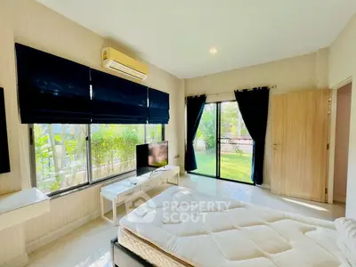 Bright bedroom with large windows, garden view, and modern furnishings.