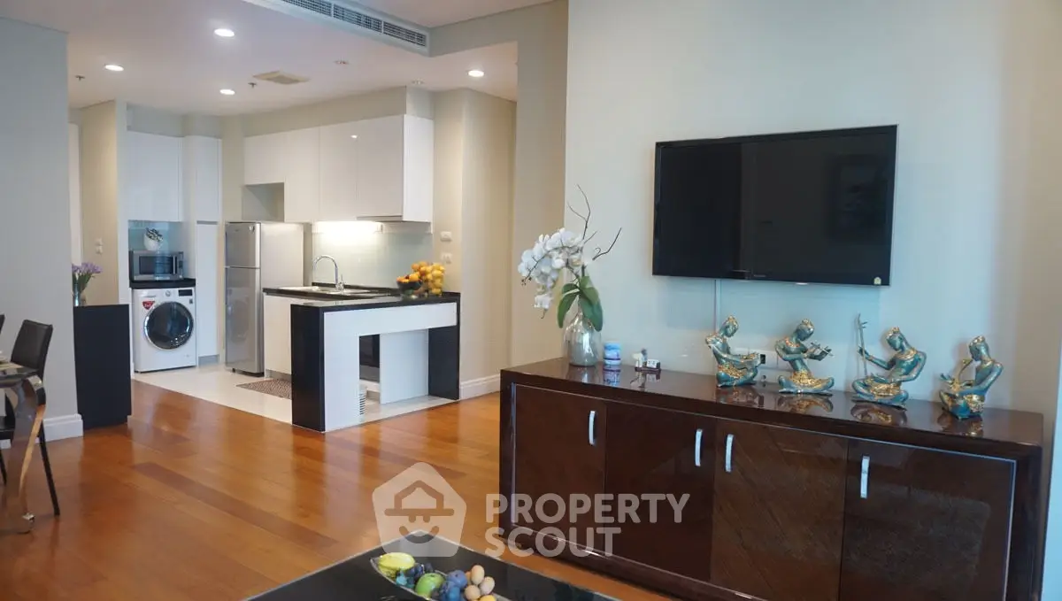 Modern living room with open kitchen, featuring sleek appliances and elegant decor.