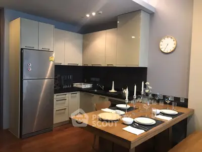 Modern kitchen with sleek cabinets and dining area, featuring stainless steel appliances and elegant table setting.