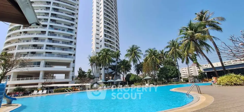 Luxurious high-rise condos with stunning pool and palm trees in tropical paradise setting.