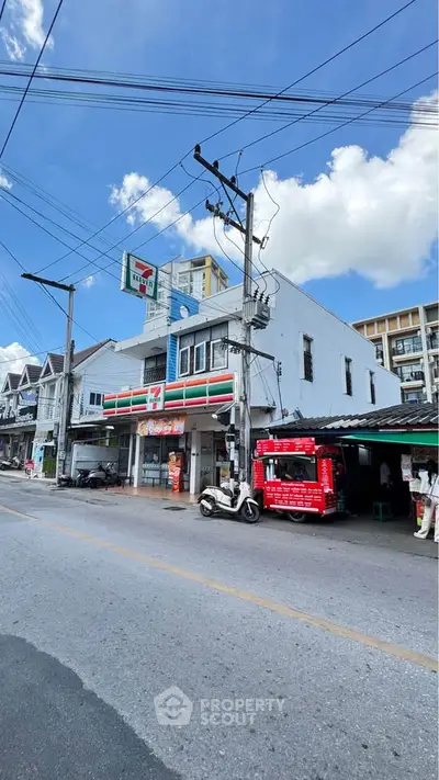 Street view of commercial building with convenience store and clear blue sky.