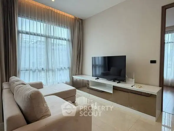 Modern living room with sleek TV setup and large window for natural light.