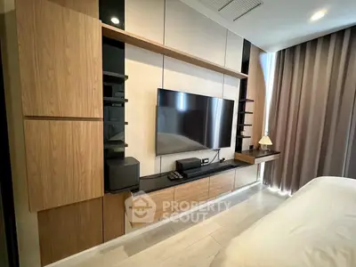 Modern bedroom with sleek wooden cabinetry and large TV, perfect for relaxation.