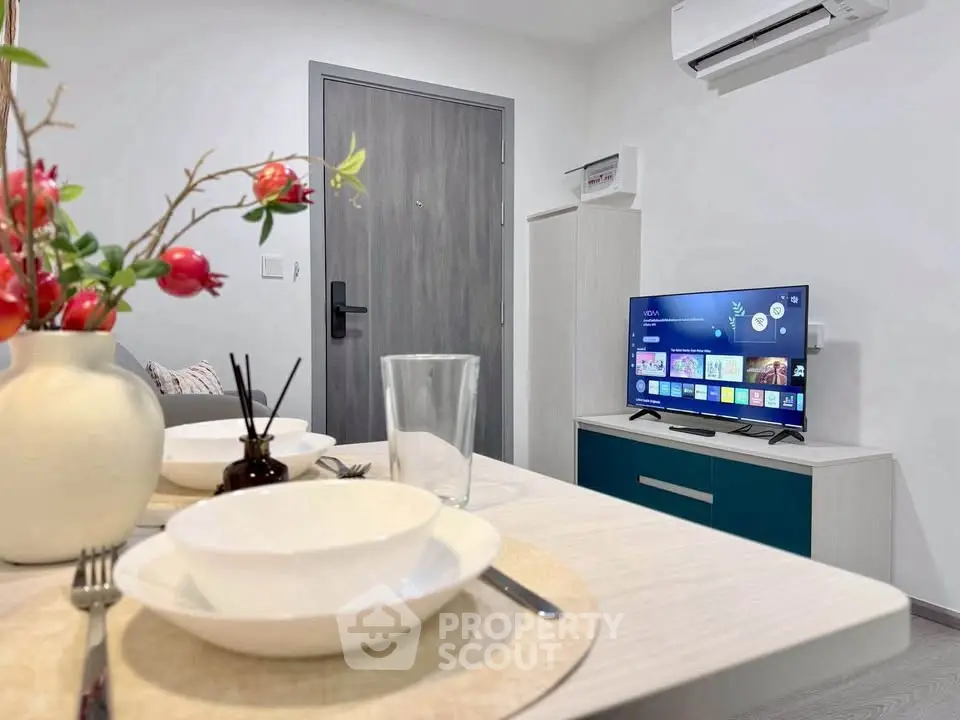 Modern living room with dining area, TV, and air conditioning in a stylish apartment.