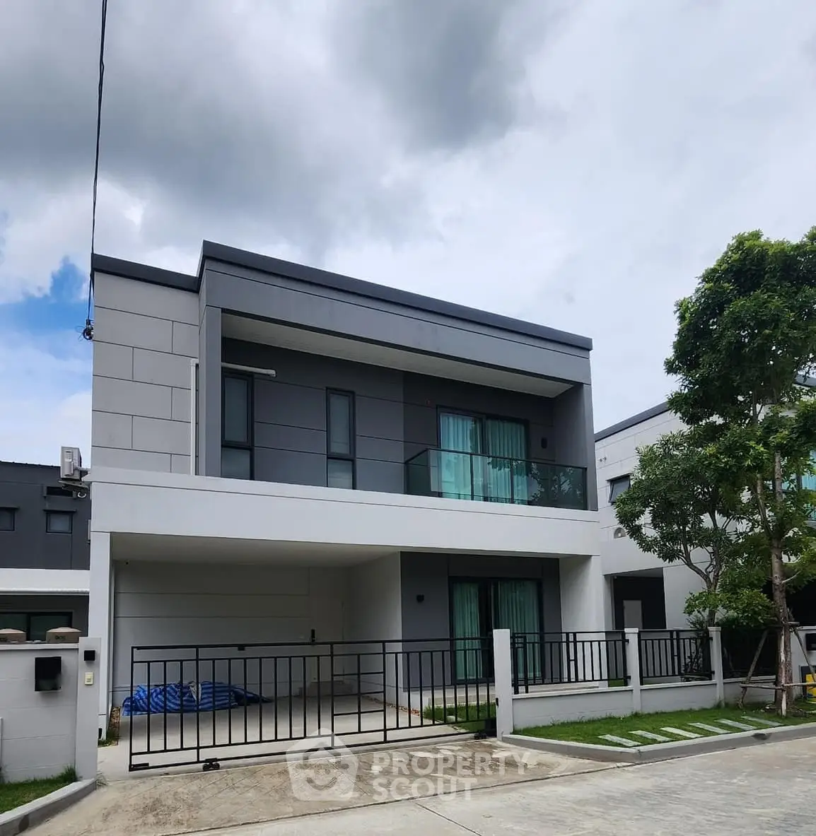 Modern two-story house with sleek design and spacious driveway in a suburban neighborhood.
