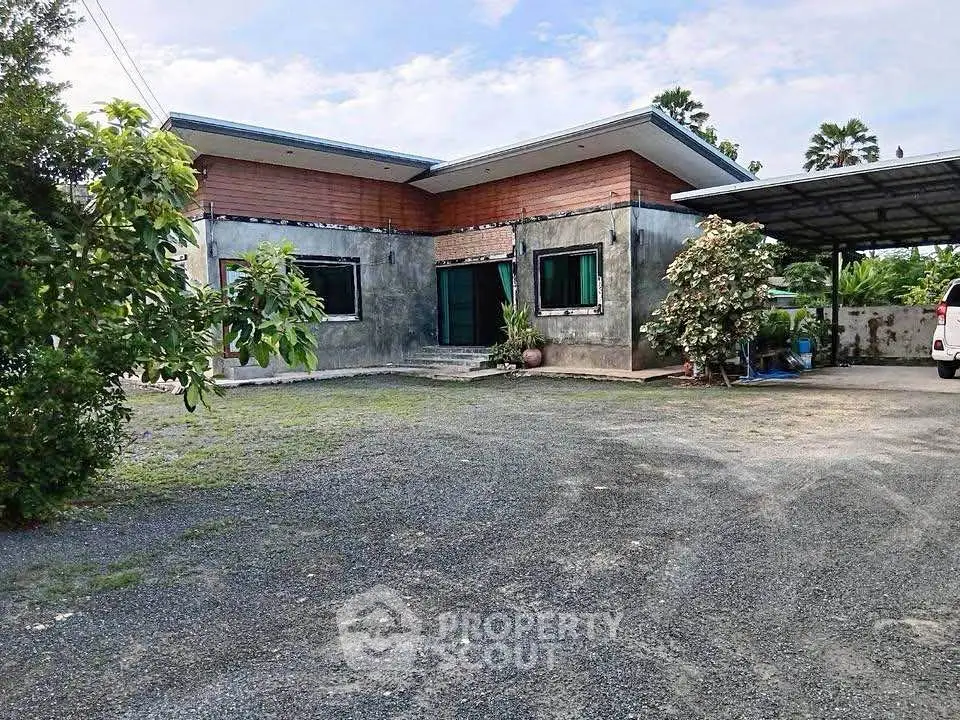 Charming modern single-story home with spacious driveway and lush greenery.