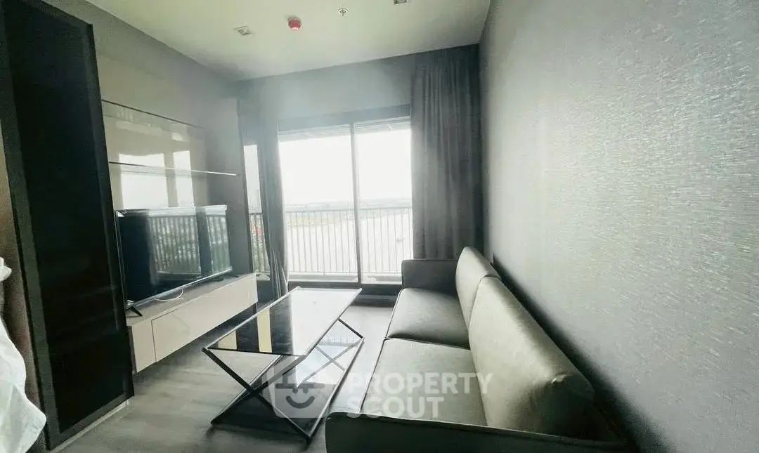 Modern living room with sleek furniture and large window offering natural light and balcony access.