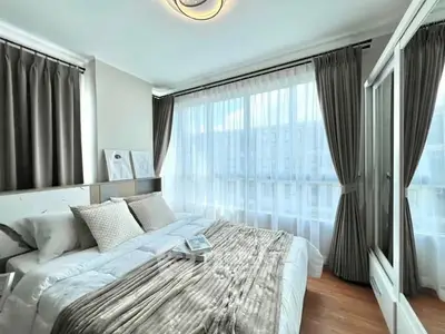 Bright and airy bedroom with large windows and elegant curtains, showcasing modern decor and cozy ambiance.