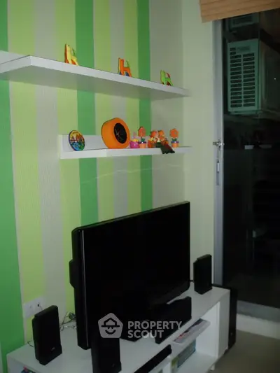 Modern living room with striped green walls, sleek TV setup, and decorative shelves.