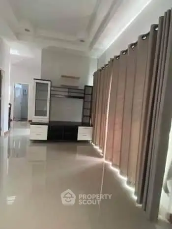 Spacious living room with modern furniture and large windows with curtains.